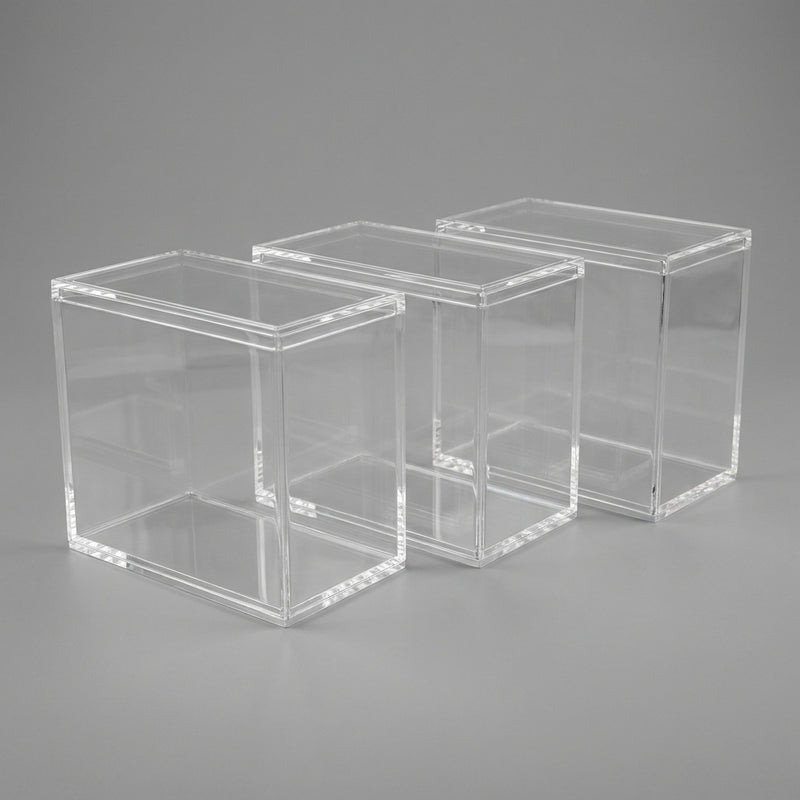 Three empty acrylic Elite Trainer Box display cases with lids on a neutral background